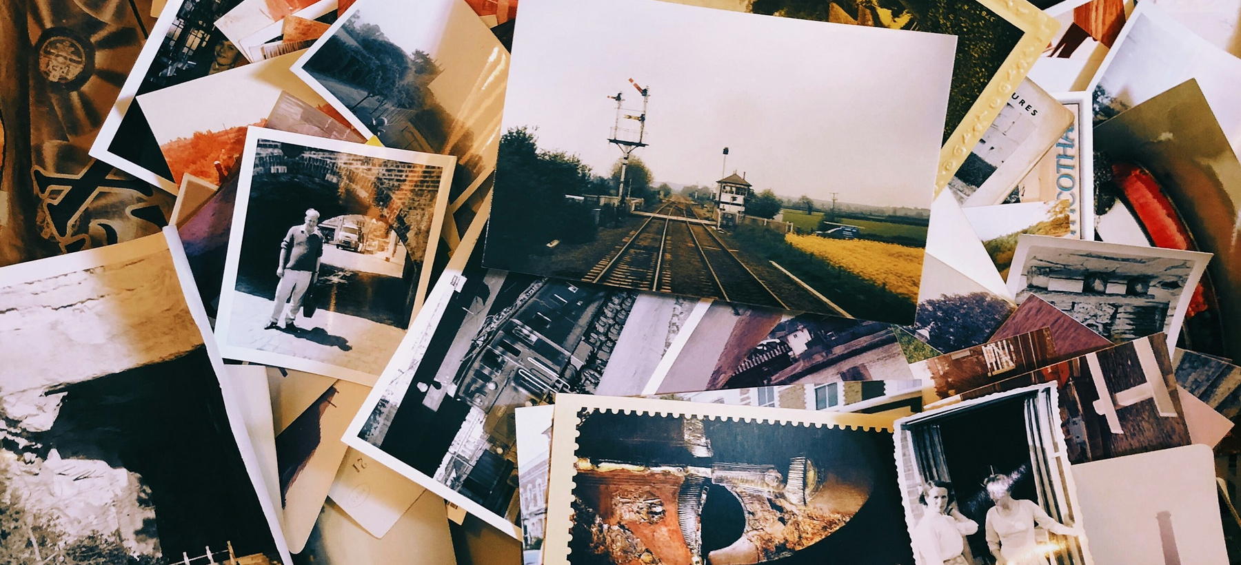 A large pile of printed family photographs and postcards spread across a table